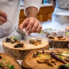 Szef kuchni serwuje danie z grzybów i ziół na drewnianych plastrach, tworząc magiczną atmosferę. To uczta godna najlepszych restauracji w Warszawie.
