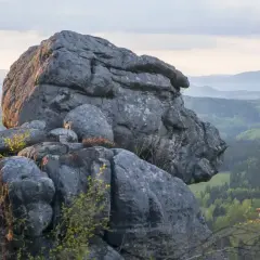 Imponujące formacje skalne w Górach Stołowych, z widokiem na zielone doliny i łagodne wzgórza w oddali.