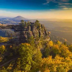 Skalny most Pravčická brána w Czechach, idealne miejsce na weekendowy wypad. Jesienne kolory lasów i zachodzące słońce tworzą magiczny widok.