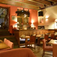 Przytulne wnętrze restauracji, gdzie zjeść w Krakowie na Rynku. Drewniane stoły, czerwone obicia i ciepłe oświetlenie tworzą atmosferę.