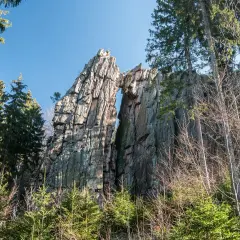 Skalny most na rudawych janowickich szlakach, otoczony drzewami.