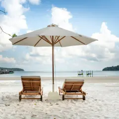 Dwie leżaki pod parasolem na piaszczystej plaży. Idealne miejsce, by zapytać, gdzie na wakacje w czerwcu.