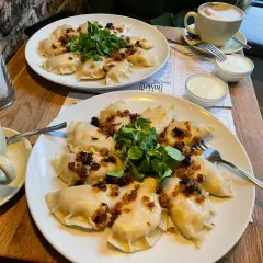 Pyszne pierogi z cebulką i zielenią to świetny pomysł, co zjeść w Poznaniu. Do tego kawa i śmietana.