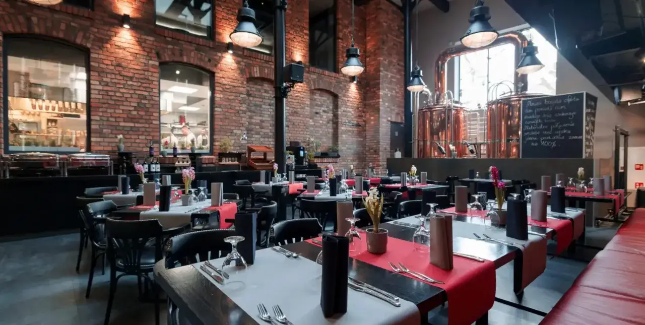Stylowe wnętrze restauracji z ceglanymi ścianami i miedzianymi kadziami. Idealne miejsce, gdzie zjeść w Katowicach, oferujące wyjątkowe doznania kulinarne.