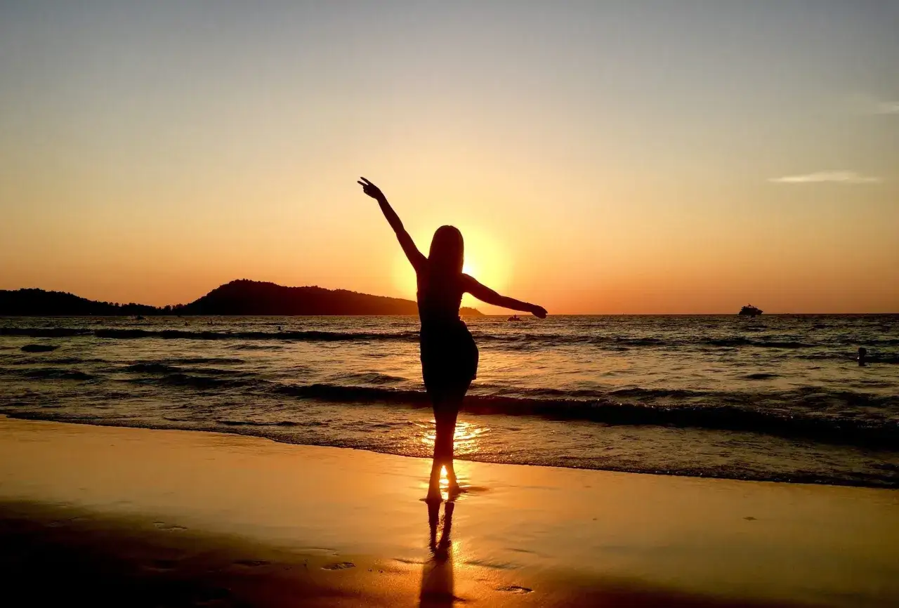 Sylwetka kobiety na plaży podczas zachodu słońca. Idealna pogoda na Phuket w listopadzie.
